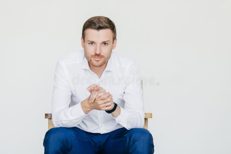 Le portrait d'intérieur de l'homme d'affaires plein d'assurance bel dans la chemise blanche et des pantalons noirs, regards avec images stock Le portrait d'intérieur de l'homme d'affaires plein d'assurance bel dans la chemise blanche et des pantalons noirs, regards avec images stock