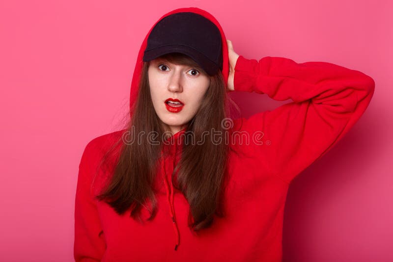 Le portrait de l'adolescent européen étonné de brune maintient sa main sur la tête, supports avec la bouche ouverte, habillée dan image libre de droits Le portrait de l'adolescent européen étonné de brune maintient sa main sur la tête, supports avec la bouche ouverte, habillée dan image libre de droits