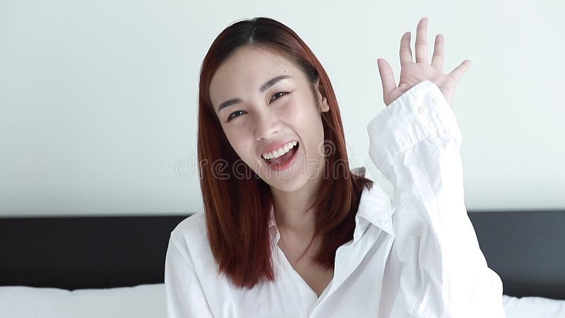 Le portrait de la belle femme brune asiatique portent le sourire blanc de chemise et l'ondulation au revoir banque de vidéos