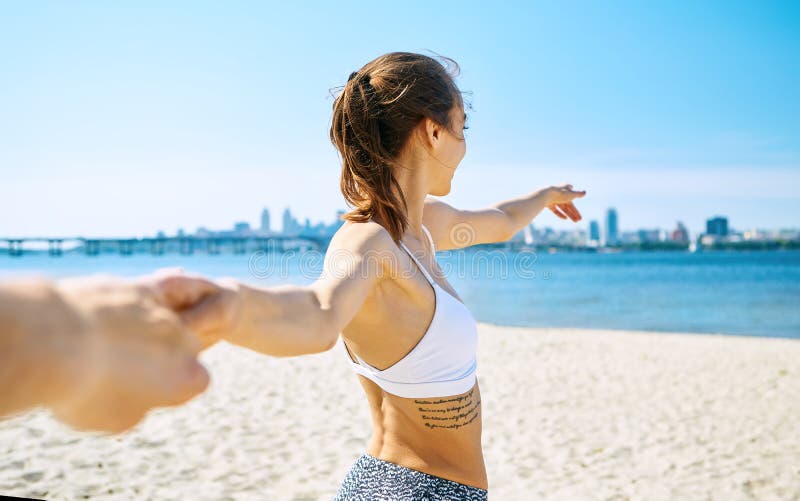 Le portrait de la belle femme heureuse sexy sur la plage de ville de sable avec le fond de mer tient quelqu'un main ?t? photos libres de droits Le portrait de la belle femme heureuse sexy sur la plage de ville de sable avec le fond de mer tient quelqu'un main ?t? photos libres de droits