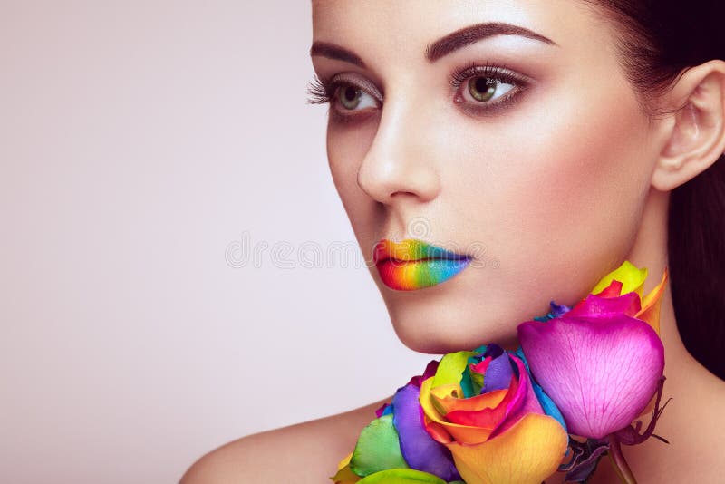 Portrait of beautiful young woman with rainbow rose. Bright colors. Vivid colorful lips. Rainbow make up. Multicolored flowers. Portrait of beautiful young woman with rainbow rose. Bright colors. Vivid colorful lips. Rainbow make up. Multicolored flowers