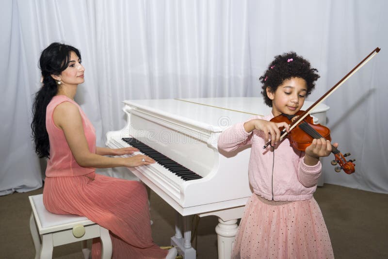Le portrait de la belle obscurité heureuse a pelé la petite fille à l'aide d'un violon tout en jouant une mélodie image libre de droits Le portrait de la belle obscurité heureuse a pelé la petite fille à l'aide d'un violon tout en jouant une mélodie image libre de droits