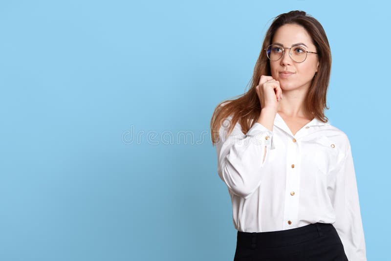 Le portrait de la jeune femme songeuse touchant son menton, a quelque chose à l'esprit, posant avec des expressions du visage réf photos stock Le portrait de la jeune femme songeuse touchant son menton, a quelque chose à l'esprit, posant avec des expressions du visage réf photos stock
