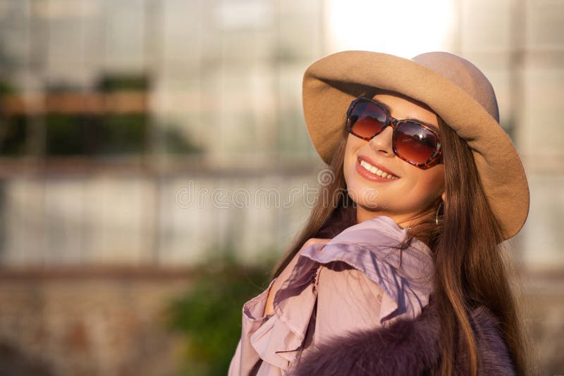 Le portrait de rue du modèle gai de brune utilise le chapeau et les lunettes de soleil, appréciant le temps chaud L'espace vide photos stock Le portrait de rue du modèle gai de brune utilise le chapeau et les lunettes de soleil, appréciant le temps chaud L'espace vide photos stock