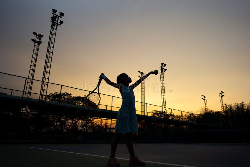 Le portrait de silhouette de la fille asiatique joue au tennis à la cour extérieure avec le ciel de coucher du soleil à l'arri photos stock Le portrait de silhouette de la fille asiatique joue au tennis à la cour extérieure avec le ciel de coucher du soleil à l'arri photos stock