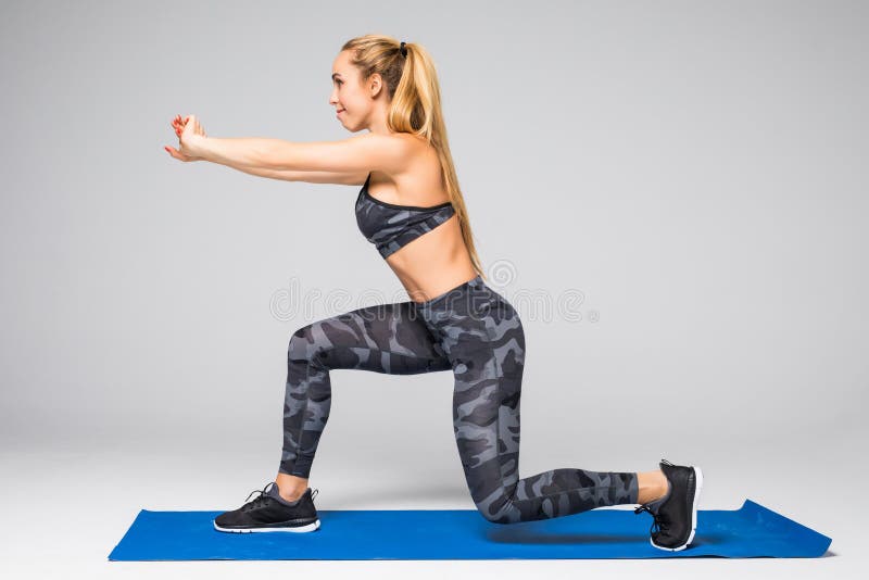 Le portrait de vue de côté de la belle jeune femme établissant contre le mur gris, faisant le yoga ou les pilates s'exercent sur photographie stock Le portrait de vue de côté de la belle jeune femme établissant contre le mur gris, faisant le yoga ou les pilates s'exercent sur photographie stock