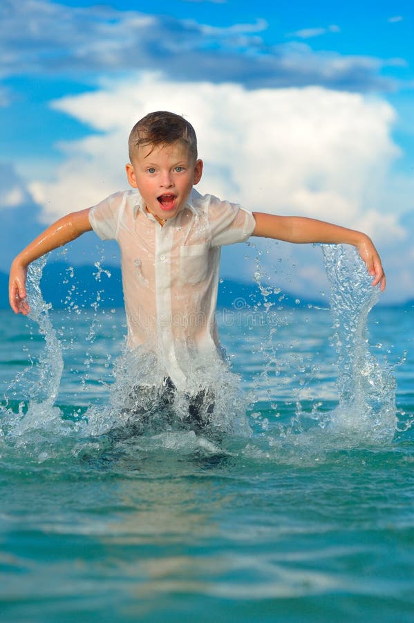 Le portrait en gros plan d'un garçon beau dans la chemise mince humide d'ajustement saute et flotte par-dessus l'eau, beaucoup d' images stock Le portrait en gros plan d'un garçon beau dans la chemise mince humide d'ajustement saute et flotte par-dessus l'eau, beaucoup d' images stock