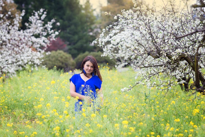 Le portrait horizontal des pruniers de floraison proches de jeune femme caucasienne de brune dans la moutarde jaune mettent en pl photo stock Le portrait horizontal des pruniers de floraison proches de jeune femme caucasienne de brune dans la moutarde jaune mettent en pl photo stock