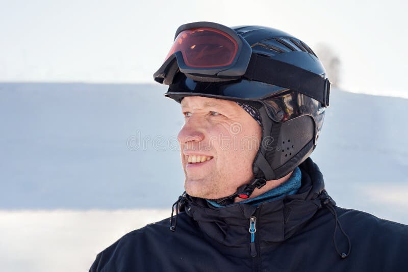 Le portrait latéral d'un homme dans un casque de ski et les lunettes de ski sur le fond d'un ski font du surf des neiges la desce image libre de droits Le portrait latéral d'un homme dans un casque de ski et les lunettes de ski sur le fond d'un ski font du surf des neiges la desce image libre de droits