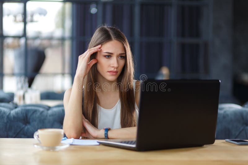 A young worker is sitting before the screen of her laptop. trying to solve some working problems. A young worker is sitting before the screen of her laptop. trying to solve some working problems.