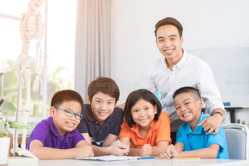 Le professeur asiatique explique une structure de corps humain au petit élève images stock Le professeur asiatique explique une structure de corps humain au petit élève images stock