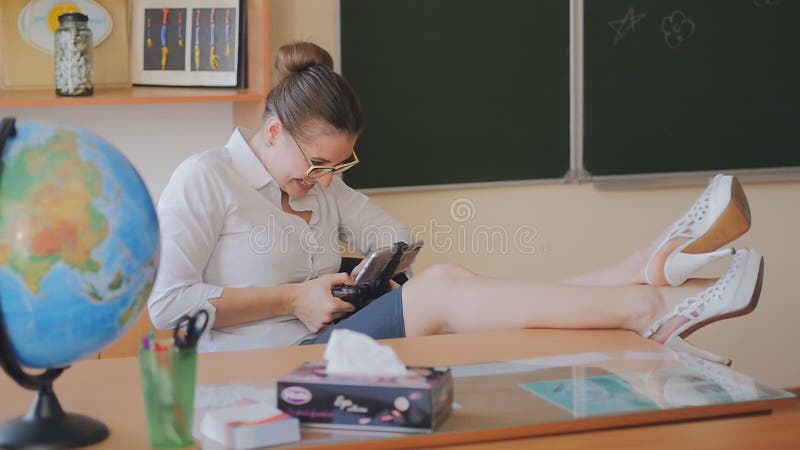 Le professeur de jeune femme joue des jeux au téléphone tout en se reposant dans la salle de classe Le professeur écrit des sms M banque de vidéos