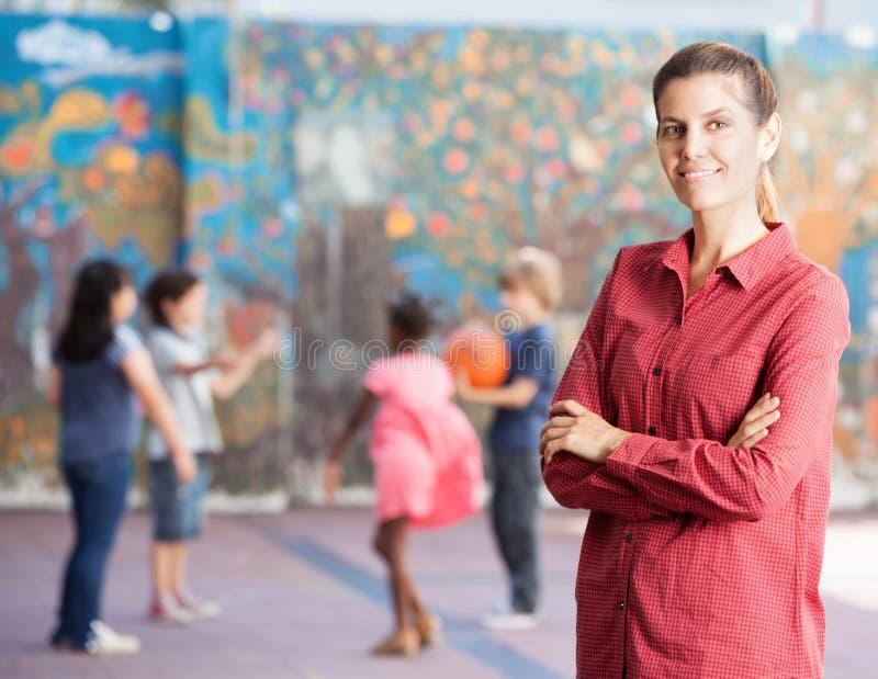 Le professeur féminin avec son école primaire badine jouer extérieur image libre de droits Le professeur féminin avec son école primaire badine jouer extérieur image libre de droits
