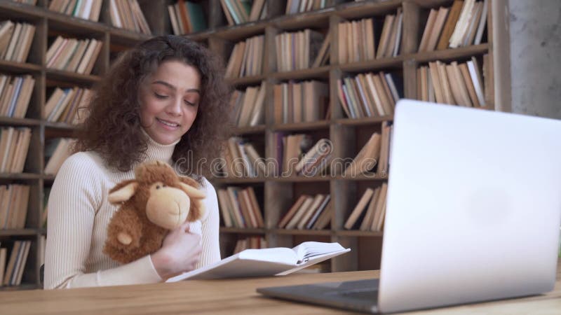 Le professeur hispanique de femme a lu l'apparence de livre pour enfants à la maternelle en ligne pour ordinateur portable. banque de vidéos