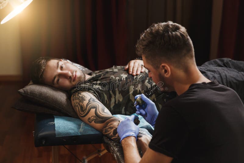 Le professionnel masculin fait tatouer dans la carlingue photo stock Le professionnel masculin fait tatouer dans la carlingue photo stock