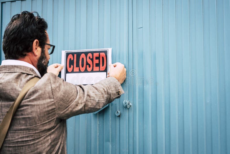 Failed business man store owner with closed signs on the door of his shop - coronavirus lockdown economy emergency crisis concept with close activity. Failed business man store owner with closed signs on the door of his shop - coronavirus lockdown economy emergency crisis concept with close activity