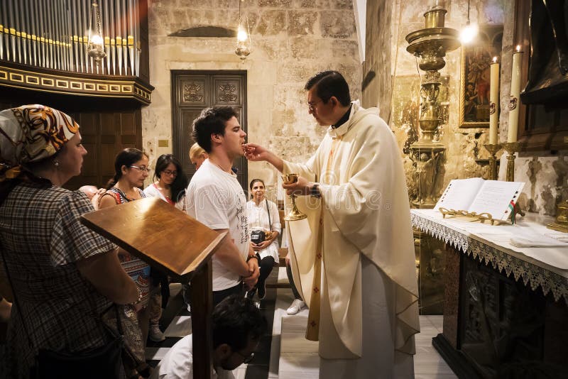 Le prêtre de l'église de la tombe sainte donne la sainte communion à l'homme fidèle avec d'autres croyants attendant leur tour jé