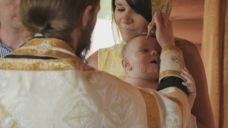 Le prêtre fait un rituel d'oindre avec de l'huile pendant le baptême infantile