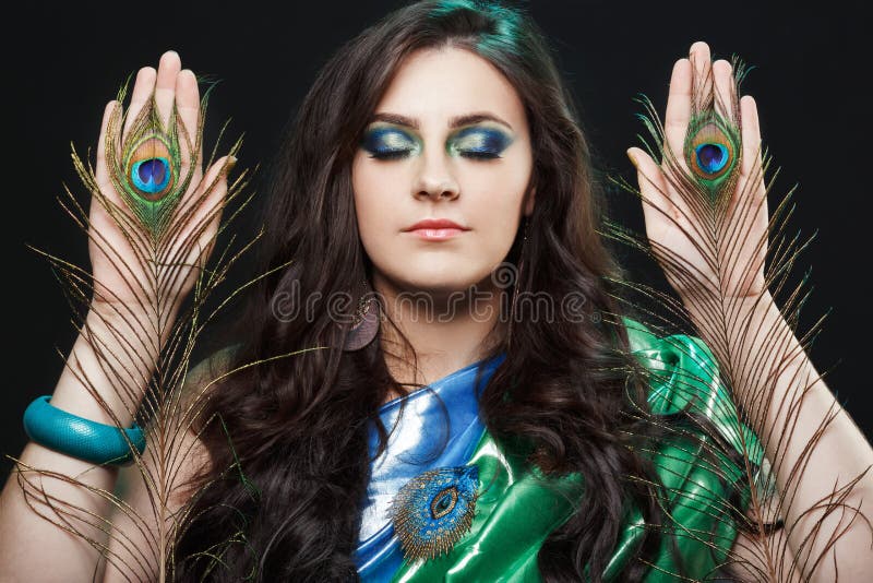 Psychic abilities psychics communicate with spirits. Beauty portrait of girl with peacock feathers, bright clothes, creative makeup. Bright colors, harmonious green black yellow blue. Dress in the style of sarees, shiny satin silk fabric. Psychic abilities psychics communicate with spirits. Beauty portrait of girl with peacock feathers, bright clothes, creative makeup. Bright colors, harmonious green black yellow blue. Dress in the style of sarees, shiny satin silk fabric.