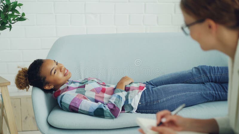 Le psychologue attentif tient la consultation avec la femme d'Afro-américain, écoute et fait des notes tandis que le client est banque de vidéos