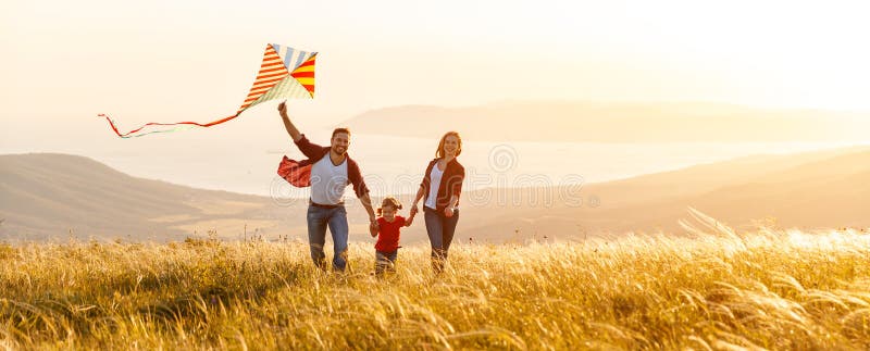 Le père de famille, la mère et la fille heureux d'enfant lancent un cerf-volant dessus