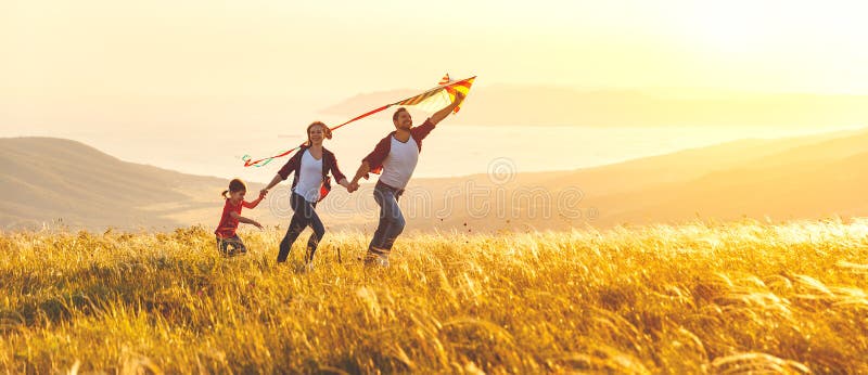 Le père de famille, la mère et la fille heureux d'enfant lancent un cerf-volant dessus