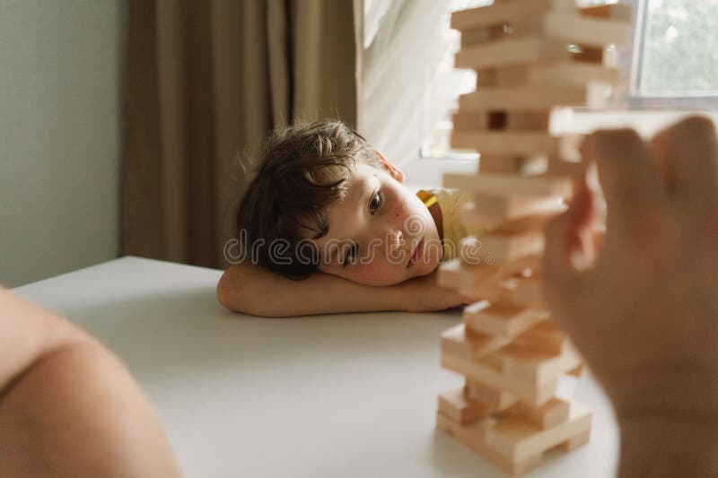 Le père et le fils jouent à la tour de bloc à l'intérieur pendant la journée. Un père et un fils jouent à une tour de blocs ensemble à l'intérieur. le jeu se déroule sur une table blanche et l'arrière-plan est hors de propos. jour des pères