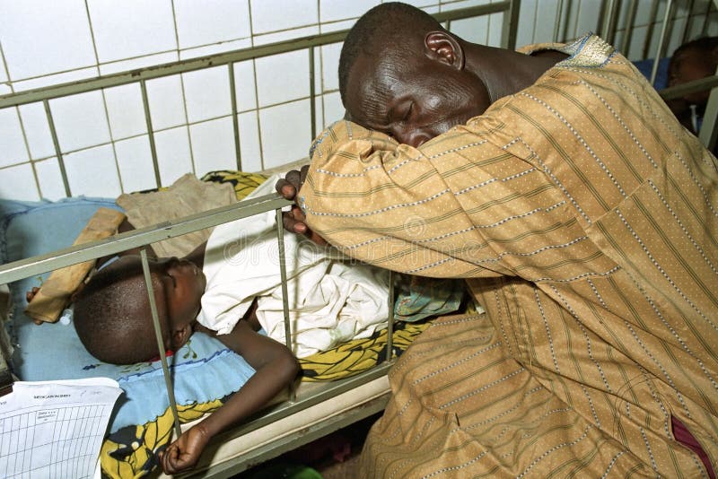 Ghana, region Brong Ahafo, city Techiman: group portrait of sleeping Ghanaian people in the Holy Family Hospital. The man is during the night fallen asleep at the sickbed of his daughter. He is the caretaker of the kid during the stay in the hospital. In a Ghanaian, African, hospital it is normal that parents or relatives care for the patient. This hospitalization is the result of an accident of the girl. Ghana, region Brong Ahafo, city Techiman: group portrait of sleeping Ghanaian people in the Holy Family Hospital. The man is during the night fallen asleep at the sickbed of his daughter. He is the caretaker of the kid during the stay in the hospital. In a Ghanaian, African, hospital it is normal that parents or relatives care for the patient. This hospitalization is the result of an accident of the girl.