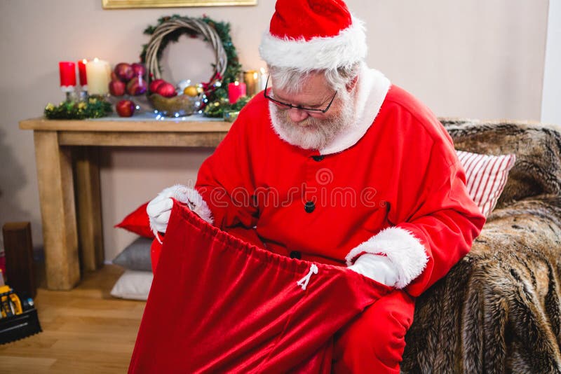 Le père noël regardant dans son sac à cadeau photo stock Le père noël regardant dans son sac à cadeau photo stock