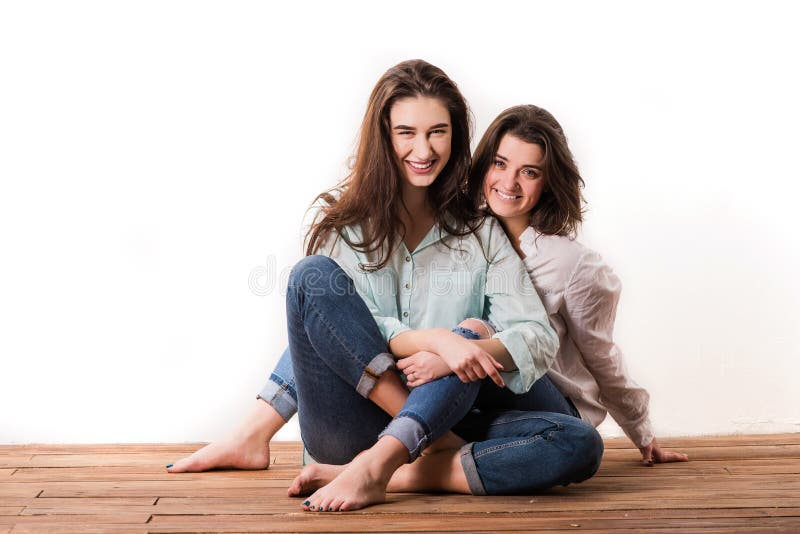 Le ragazze attraenti si siedono al pavimento di legno negli abbracci immagine stock libera da diritti