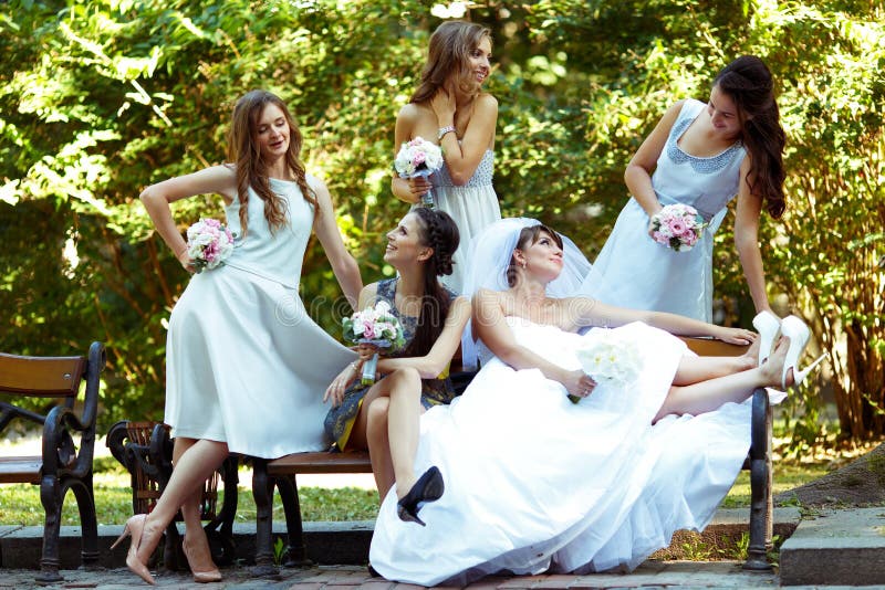 Le ragazze e la sposa graziose parlano la seduta sul banco immagine stock libera da diritti Le ragazze e la sposa graziose parlano la seduta sul banco immagine stock libera da diritti