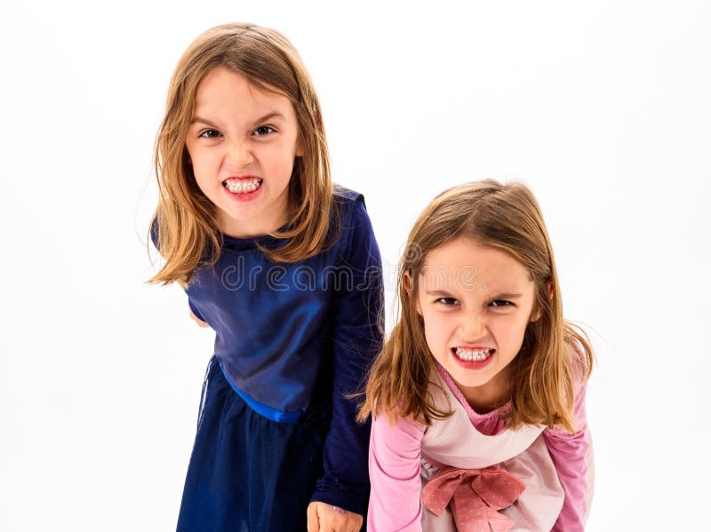 Twin girls are angry, mad and disobedient with bad behavior. Children making the act of insubordination and disobedience, yelling, showing teeth, behaving crazy. Twin girls are angry, mad and disobedient with bad behavior. Children making the act of insubordination and disobedience, yelling, showing teeth, behaving crazy.