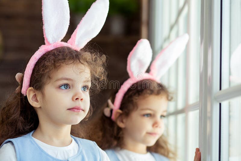 Le ragazze sveglie del piccolo bambino gemella le orecchie d'uso del coniglietto sul giorno di Pasqua Sorella che esamina finestr fotografie stock libere da diritti Le ragazze sveglie del piccolo bambino gemella le orecchie d'uso del coniglietto sul giorno di Pasqua Sorella che esamina finestr fotografie stock libere da diritti
