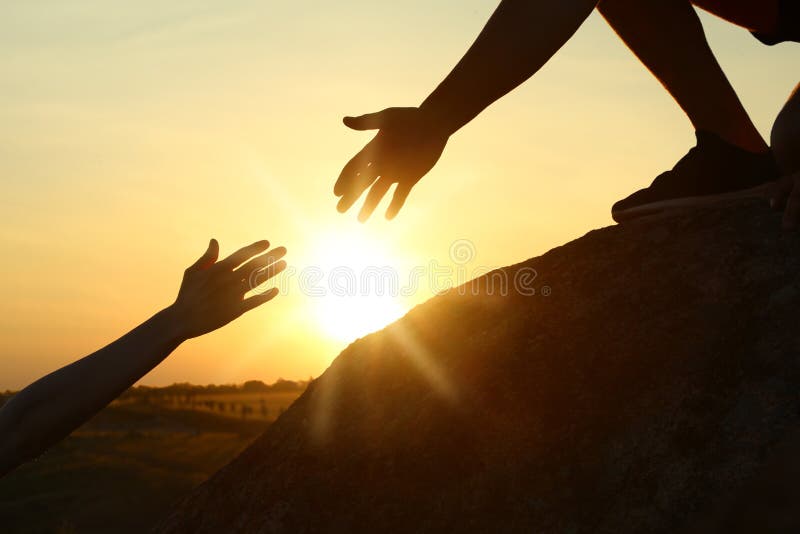 Hiker helping friend outdoors at sunset. Help and support concept. Hiker helping friend outdoors at sunset. Help and support concept