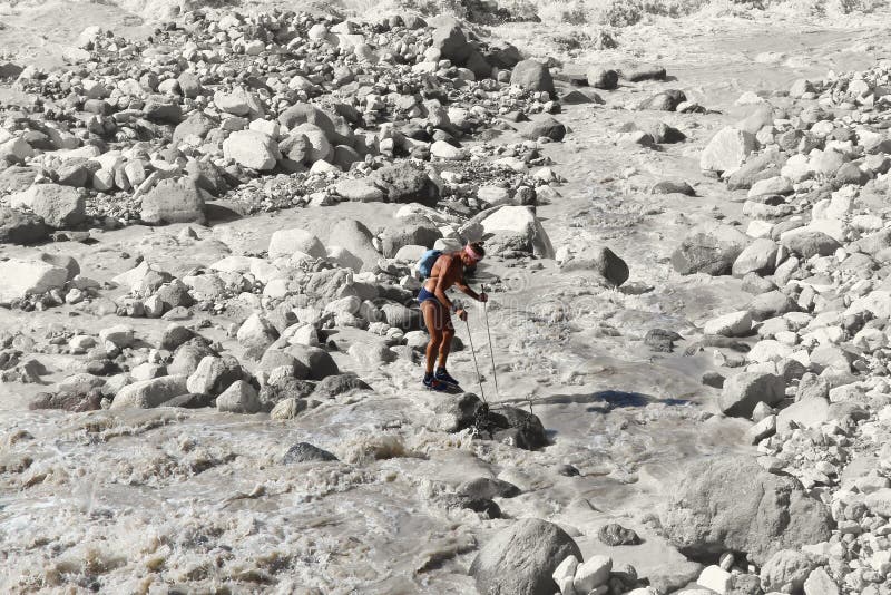 Le randonneur se tient sur une roche au beau milieu d'une rivière faisante rage de montagne images libres de droits Le randonneur se tient sur une roche au beau milieu d'une rivière faisante rage de montagne images libres de droits