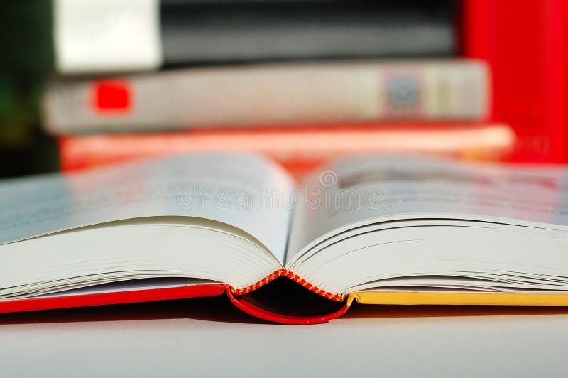 An opened book with pile of books beside it. An opened book with pile of books beside it