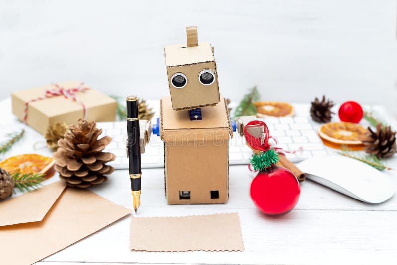 Le robot écrit des félicitations de stylo sur une carte postale avec Noël photos libres de droits Le robot écrit des félicitations de stylo sur une carte postale avec Noël photos libres de droits