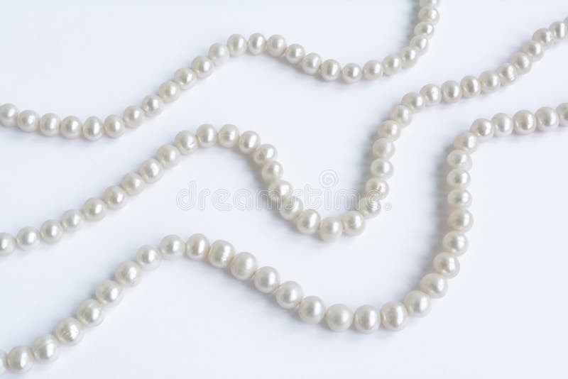 Le résumé a arrangé trois rangées de collier pâle naturel de perle sur le blanc