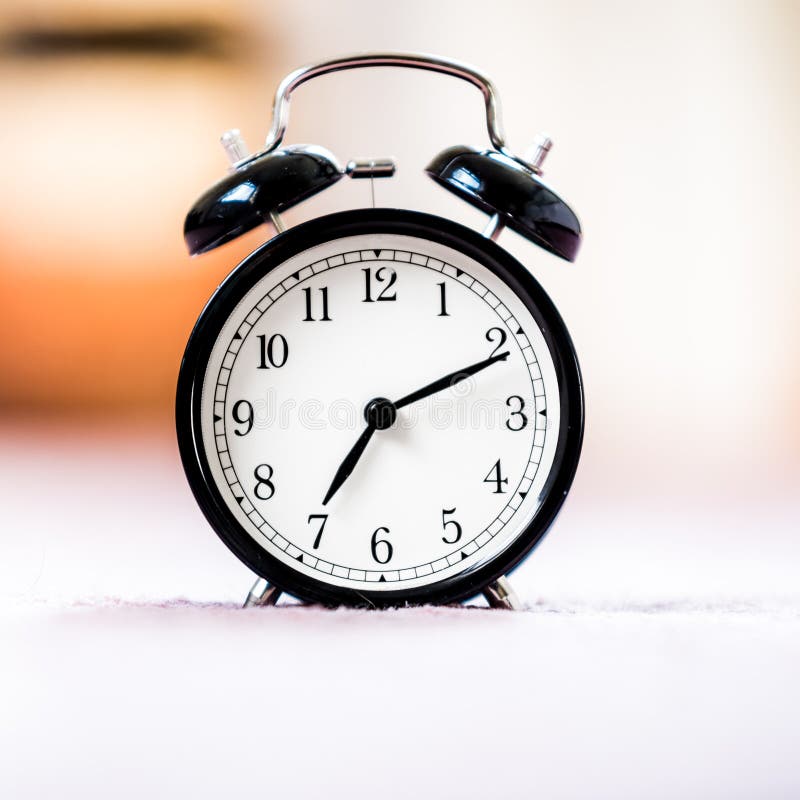 Le réveil noir de cru de la vie montre toujours le 7h du matin sur le fond lumineux de bokeh avec l'espace de copie Rétro horloge photo stock Le réveil noir de cru de la vie montre toujours le 7h du matin sur le fond lumineux de bokeh avec l'espace de copie Rétro horloge photo stock