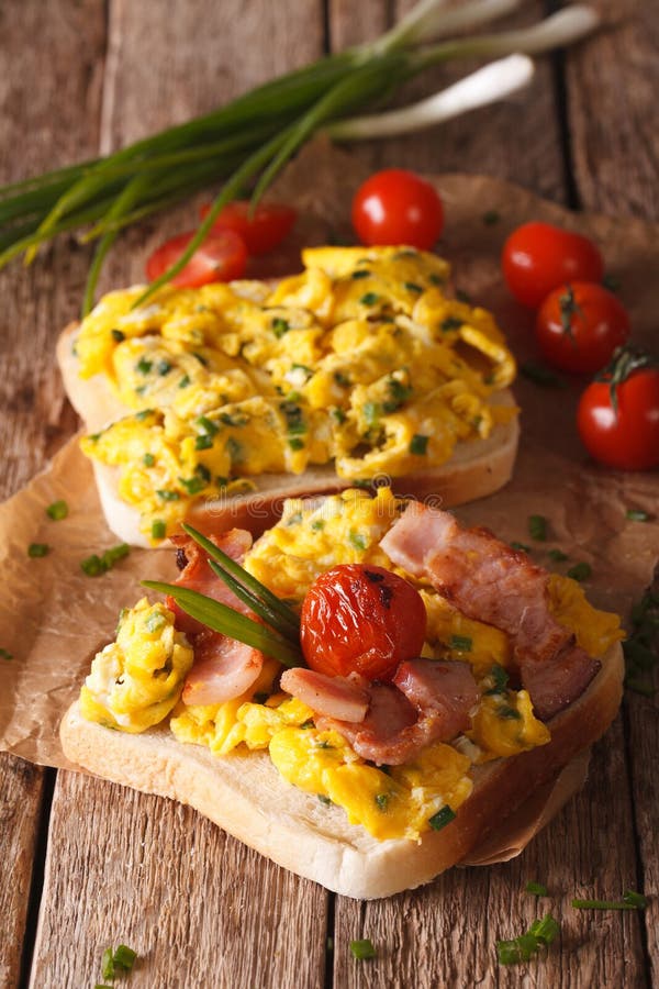 Le sandwich fait maison avec les oeufs brouillés, le lard et les tomates se ferment image libre de droits Le sandwich fait maison avec les oeufs brouillés, le lard et les tomates se ferment image libre de droits