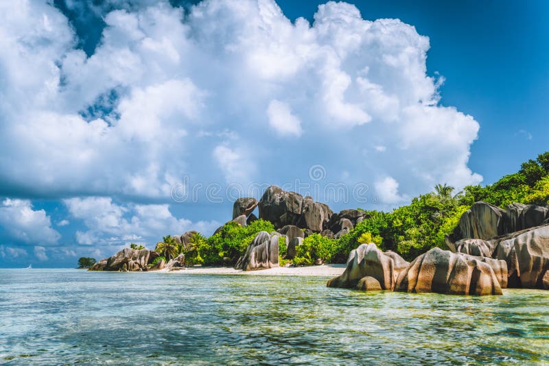 La Digue island, Seychelles. Beautiful vacation cloudscape on paradise Anse Source d&#x27;Argent beach with shallow blue lagoon, granite boulders in background. La Digue island, Seychelles. Beautiful vacation cloudscape on paradise Anse Source d&#x27;Argent beach with shallow blue lagoon, granite boulders in background.