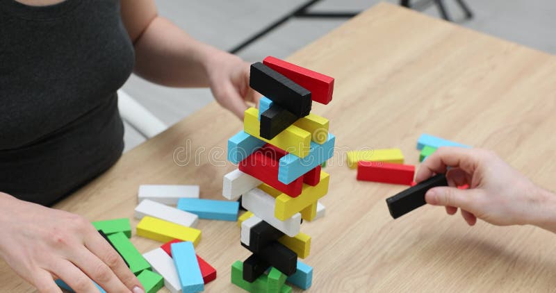 Le signore costruiscono con cura torre con blocchi di legno colorati archivi video