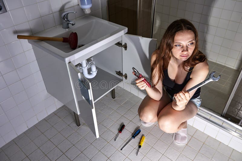 Jeune Femme Bouleversée à L'aide D'un Piston Pour Déboucher Le Drain De L' évier Dans La Cuisine Au-dessus De La Vue