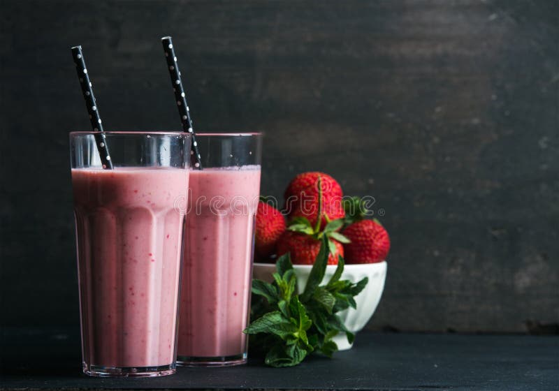 Le smoothie de fraise et de menthe en verres grands, braillent des baies fraîches sur le fond en bois rustique foncé photographie stock Le smoothie de fraise et de menthe en verres grands, braillent des baies fraîches sur le fond en bois rustique foncé photographie stock