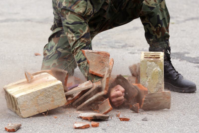 Le soldat dans l'uniforme frappe des briques image stock Le soldat dans l'uniforme frappe des briques image stock