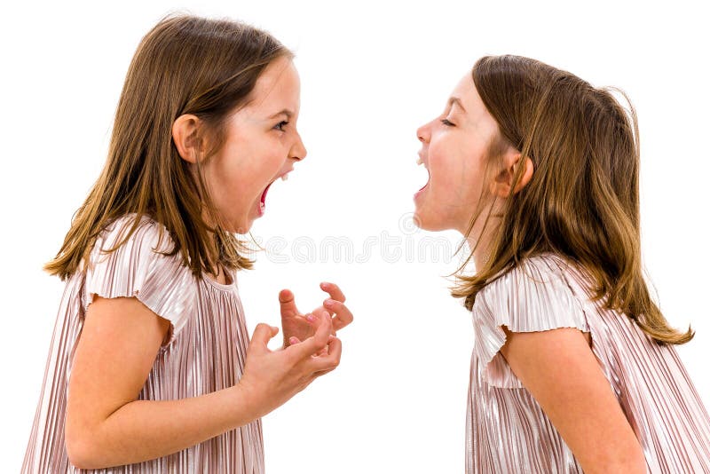 Identical twin girls sisters are arguing yelling at each other. Angry girls are shouting, yelling and arguing with emotional expression on faces. Frontal profile view of children. Isolated on white. Identical twin girls sisters are arguing yelling at each other. Angry girls are shouting, yelling and arguing with emotional expression on faces. Frontal profile view of children. Isolated on white