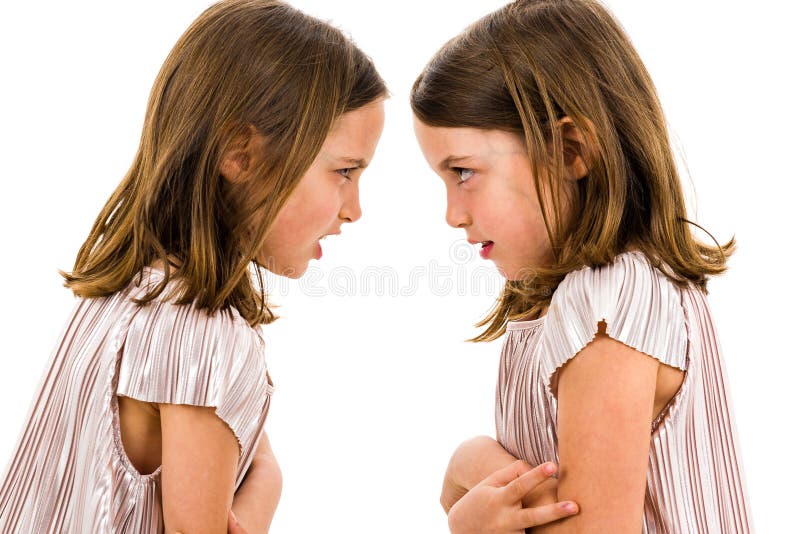 Identical twin girls sisters are arguing yelling at each other. Angry girls are shouting, yelling and arguing with emotional expression on faces. Frontal profile view of children. Isolated on white. Identical twin girls sisters are arguing yelling at each other. Angry girls are shouting, yelling and arguing with emotional expression on faces. Frontal profile view of children. Isolated on white