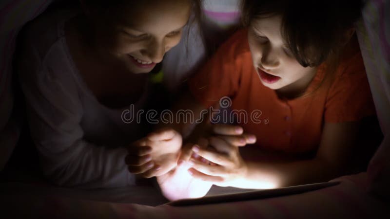 Le sorelle giocano online sul tablet di notte