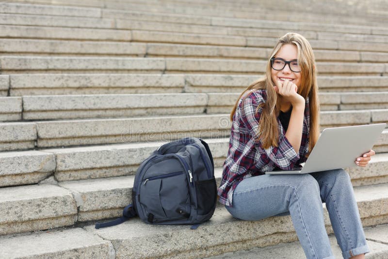 Le studentsammanträde på trappa genom att använda bärbara datorn arkivfoto Le studentsammanträde på trappa genom att använda bärbara datorn arkivfoto