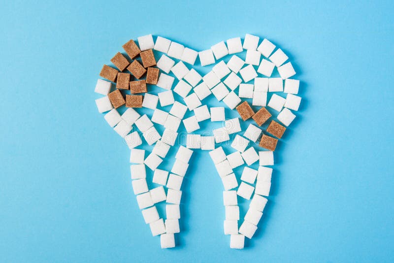 Sugar destroys the tooth enamel and leads to tooth decay. Tooth made of white sugar cubes and caries made of brown sugar cubes. Top view. Close up. Sugar destroys the tooth enamel and leads to tooth decay. Tooth made of white sugar cubes and caries made of brown sugar cubes. Top view. Close up